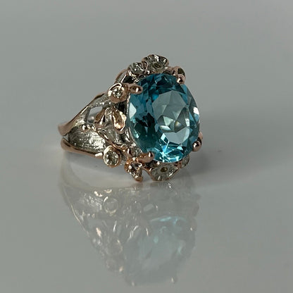 Silver ring with a blue topaz gemstone on a reflective surface