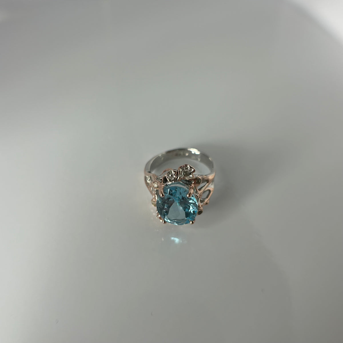 Silver ring with a blue gemstone on a light gray background