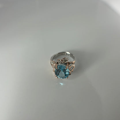 Silver ring with a blue gemstone on a light gray background