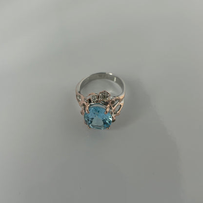Silver ring with a blue topaz gemstone on a light gray background