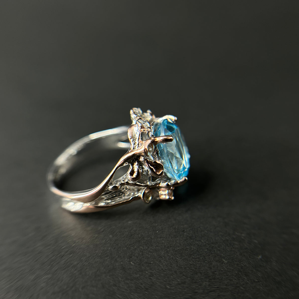 Silver ring with a blue gemstone on a black background