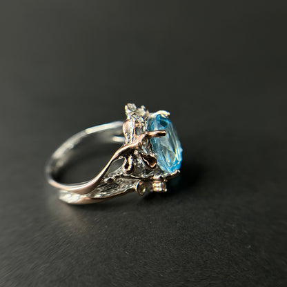 Silver ring with a blue gemstone on a black background