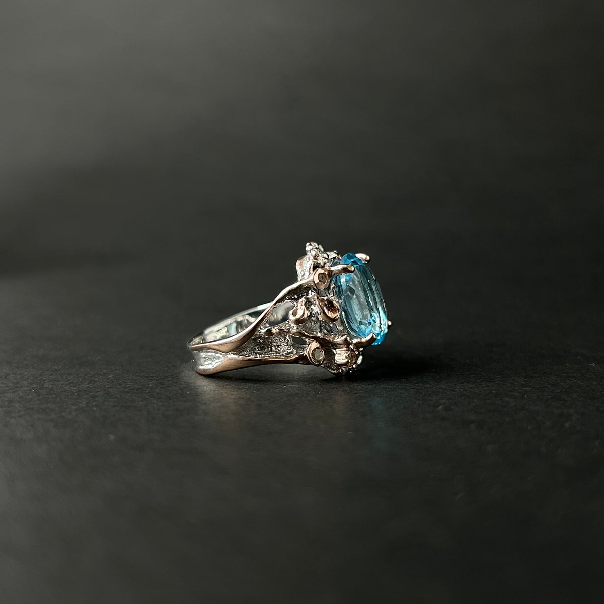 Silver ring with a blue gemstone on a dark background