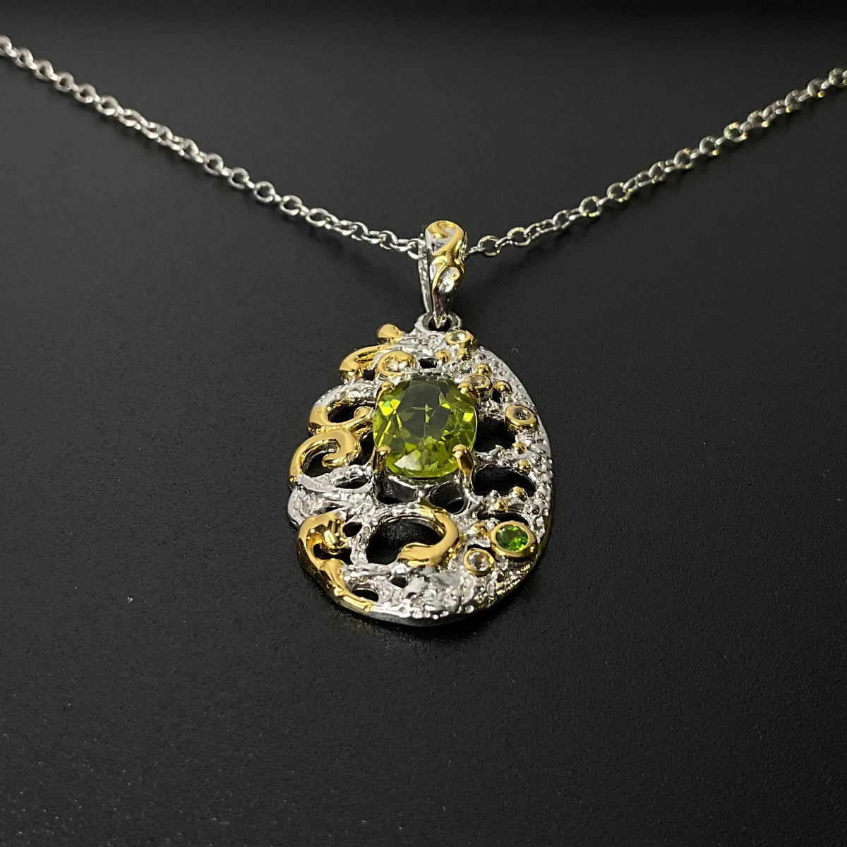 Jewelry pendant with green gemstone on a chain against a dark background