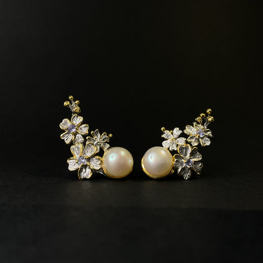 Pair of floral silver earrings with pearls on a black background