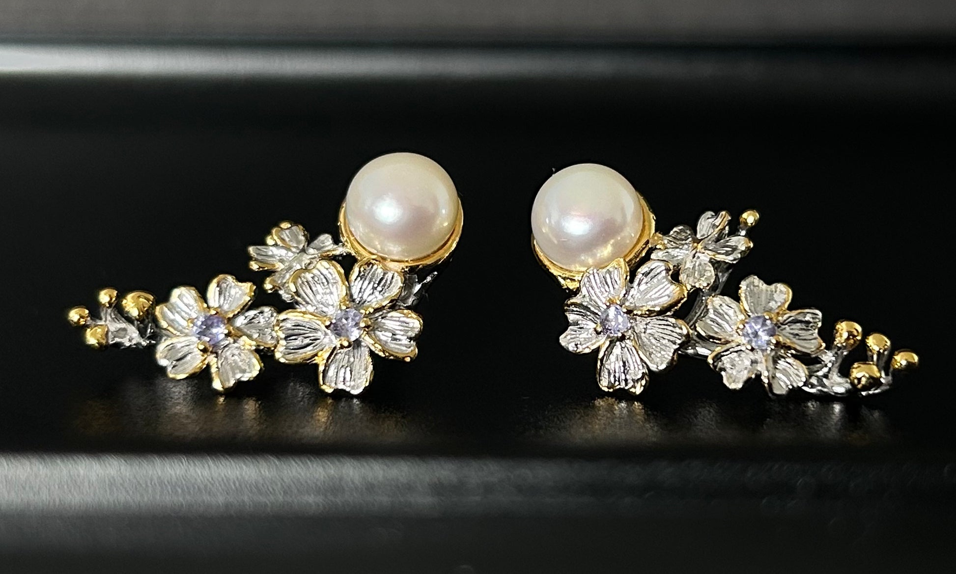 Pair of floral earrings with pearls on a black background