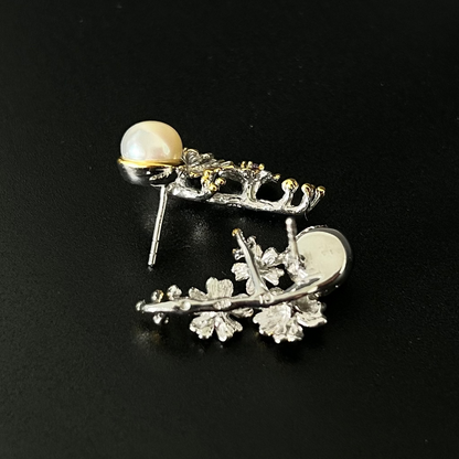 Silver leaf-shaped earring with a pearl on a black background