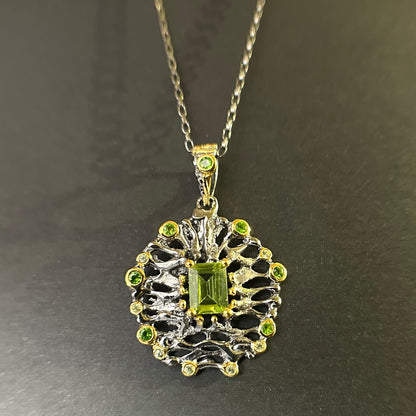 Silver pendant with green gemstones on a chain against a dark background