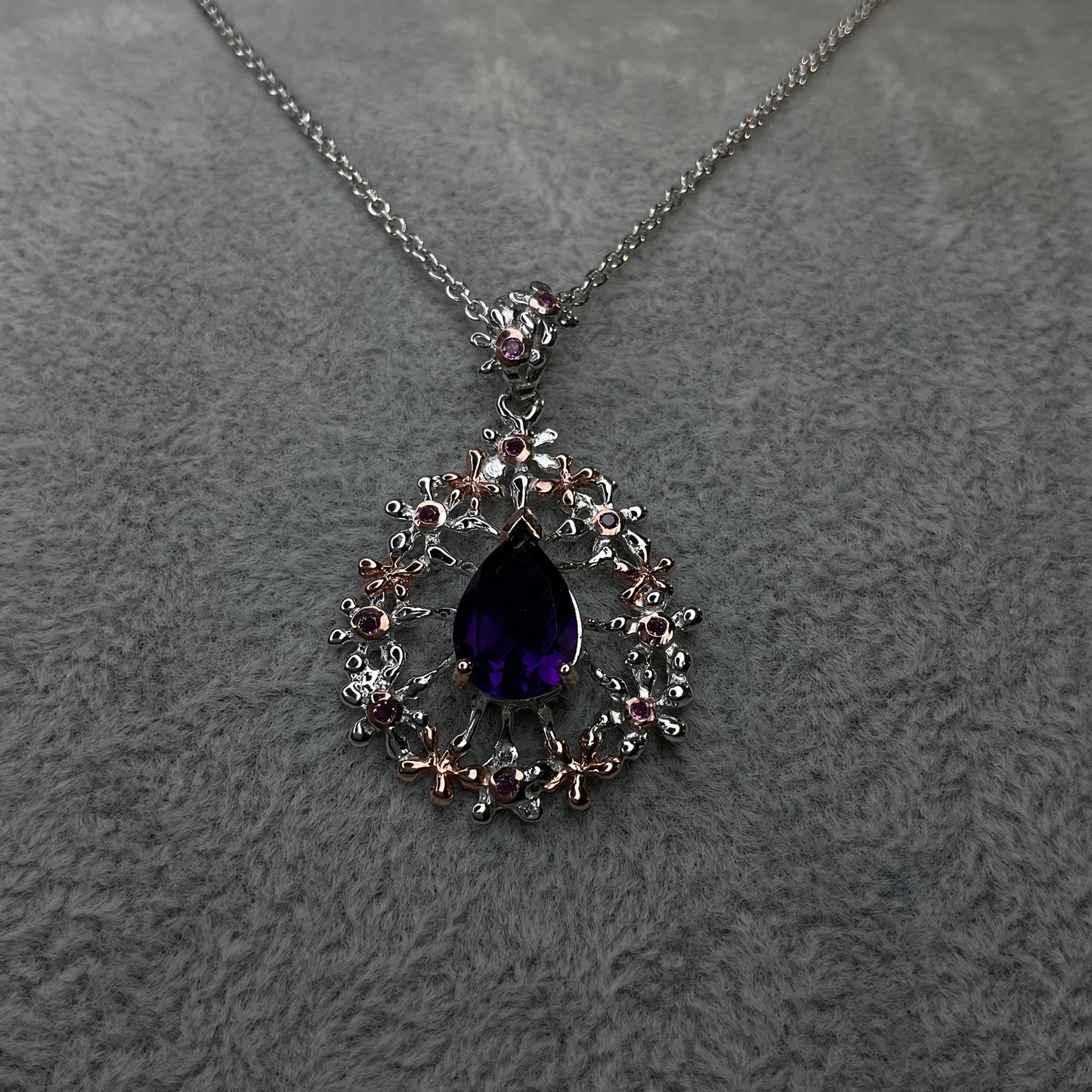 Necklace with a purple teardrop pendant on a gray textured background