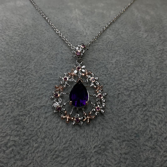 Necklace with a purple teardrop pendant on a gray textured background