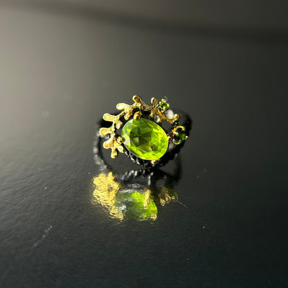 Silver and gold ring with a green peridot gemstone on a black background