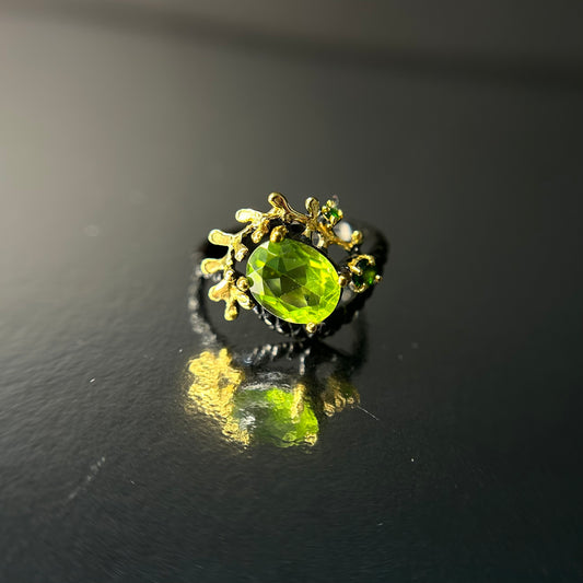 Silver and gold ring with a green peridot gemstone on a black background