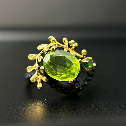 Siiver and Gold ring with a green gemstone on a black background