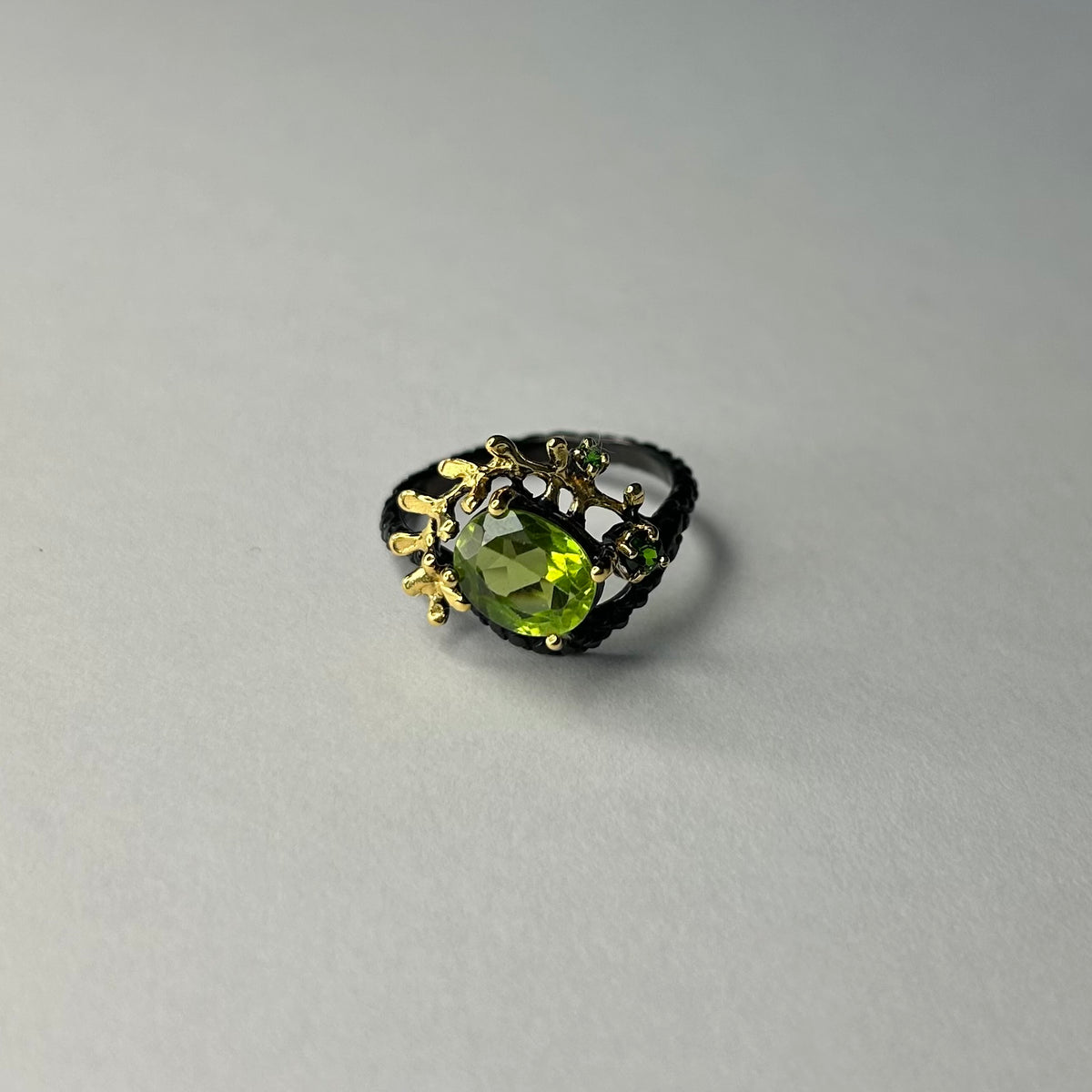 Ring with a green gemstone and gold accents on a gray background