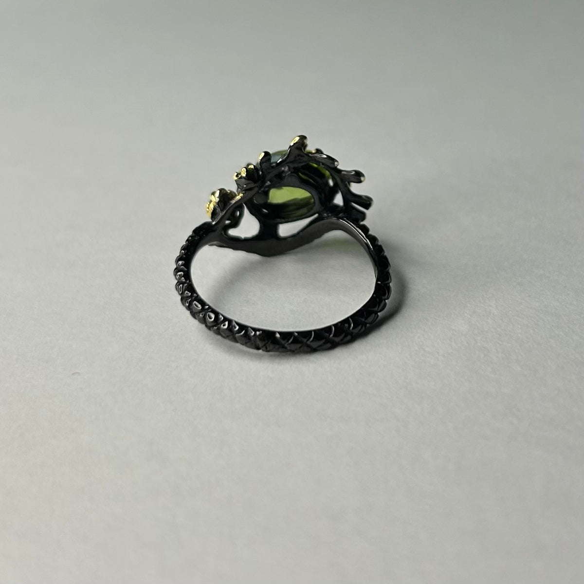 Silver ring with a green gemstone on a gray background