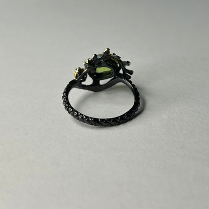 Silver ring with a green gemstone on a gray background