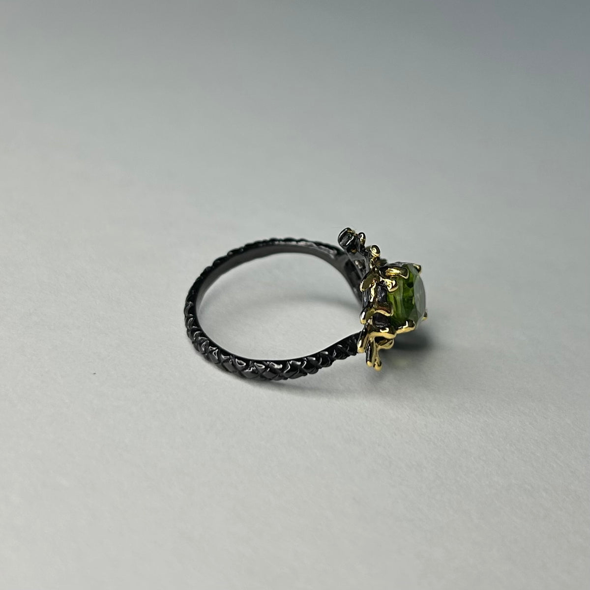 Ring with a green gemstone on a gray background