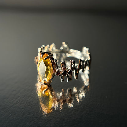 Silver ring with a yellow Citrine gemstone on a reflective surface