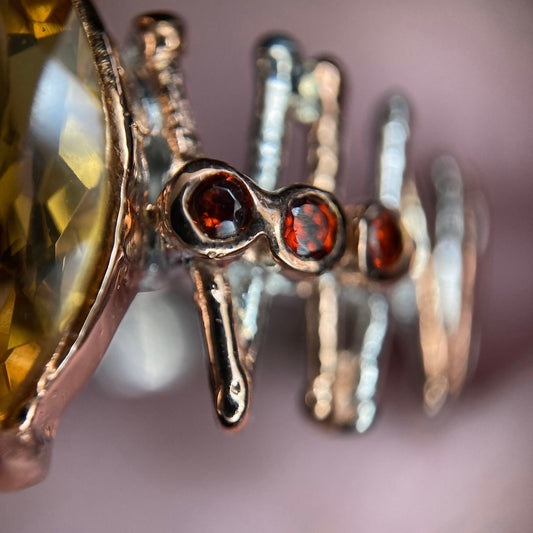 Close-up of a silver ring with red garnet  gemstones on a blurred background