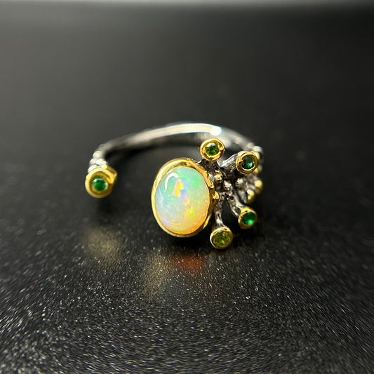 Silver and gold ring with an opal stone on a black background