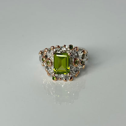 Silver ring with a green peridot gemstone and small accents on a gray background