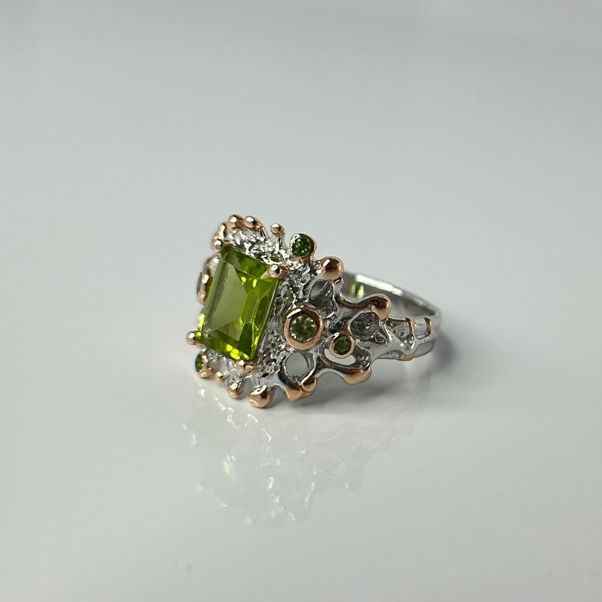 Silver ring with a green gemstone on a light gray background