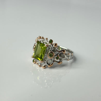 Silver ring with a green gemstone on a light gray background