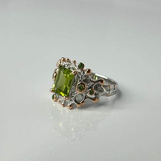 Silver ring with a green gemstone on a light gray background