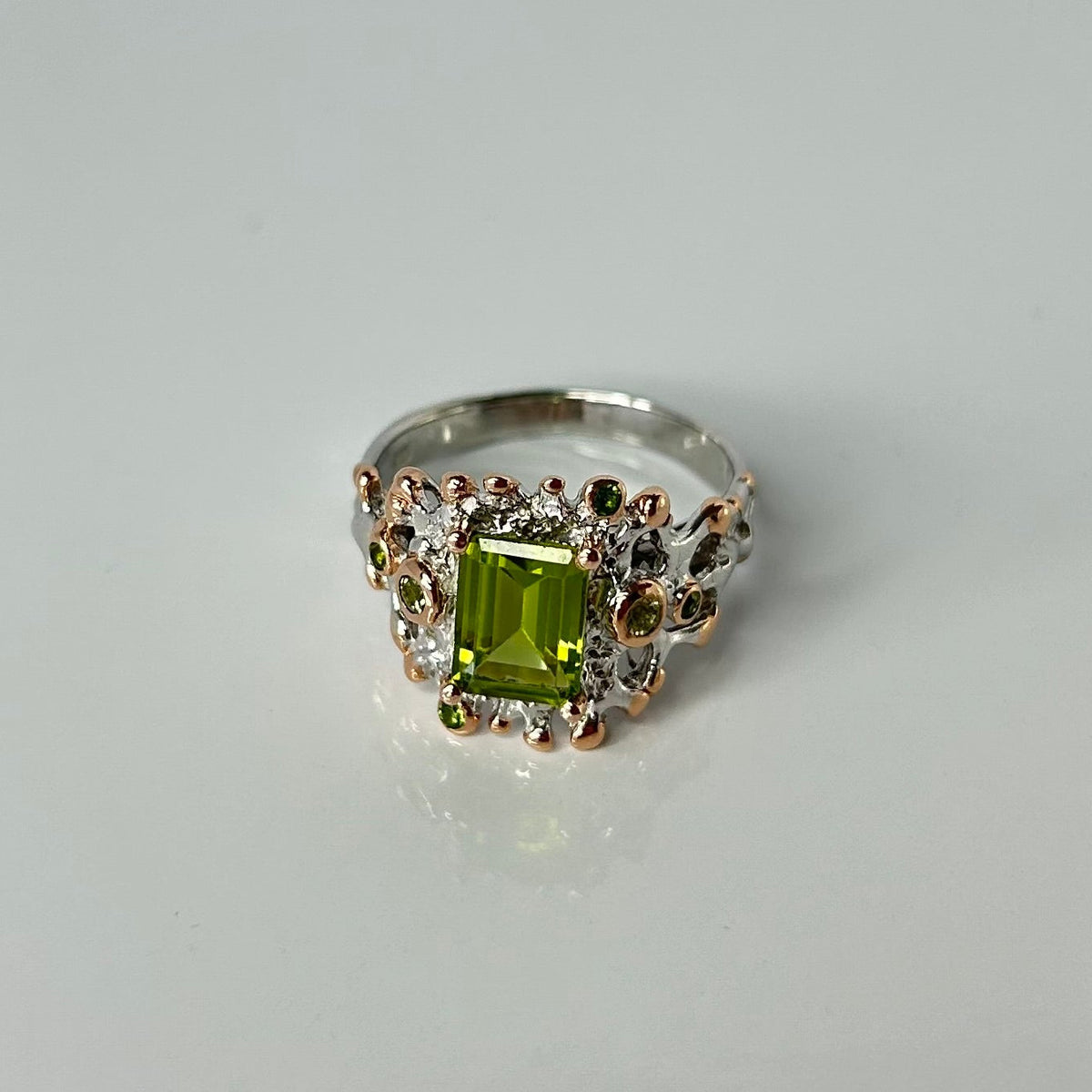 Silver ring with a green gemstone on a white background