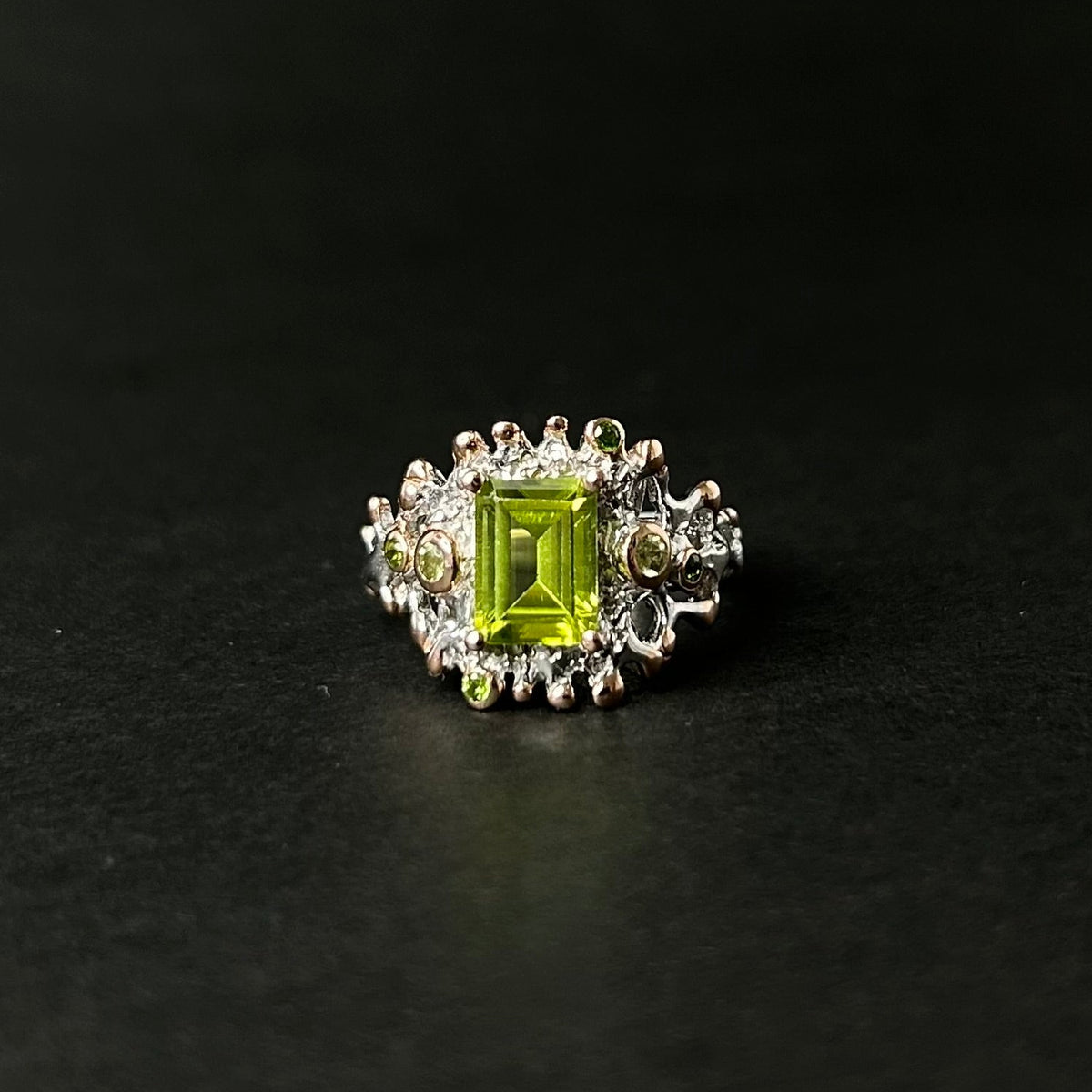 Silver ring with a green peridot gemstone on a black background