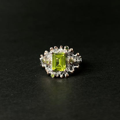 Silver ring with a green peridot gemstone on a black background