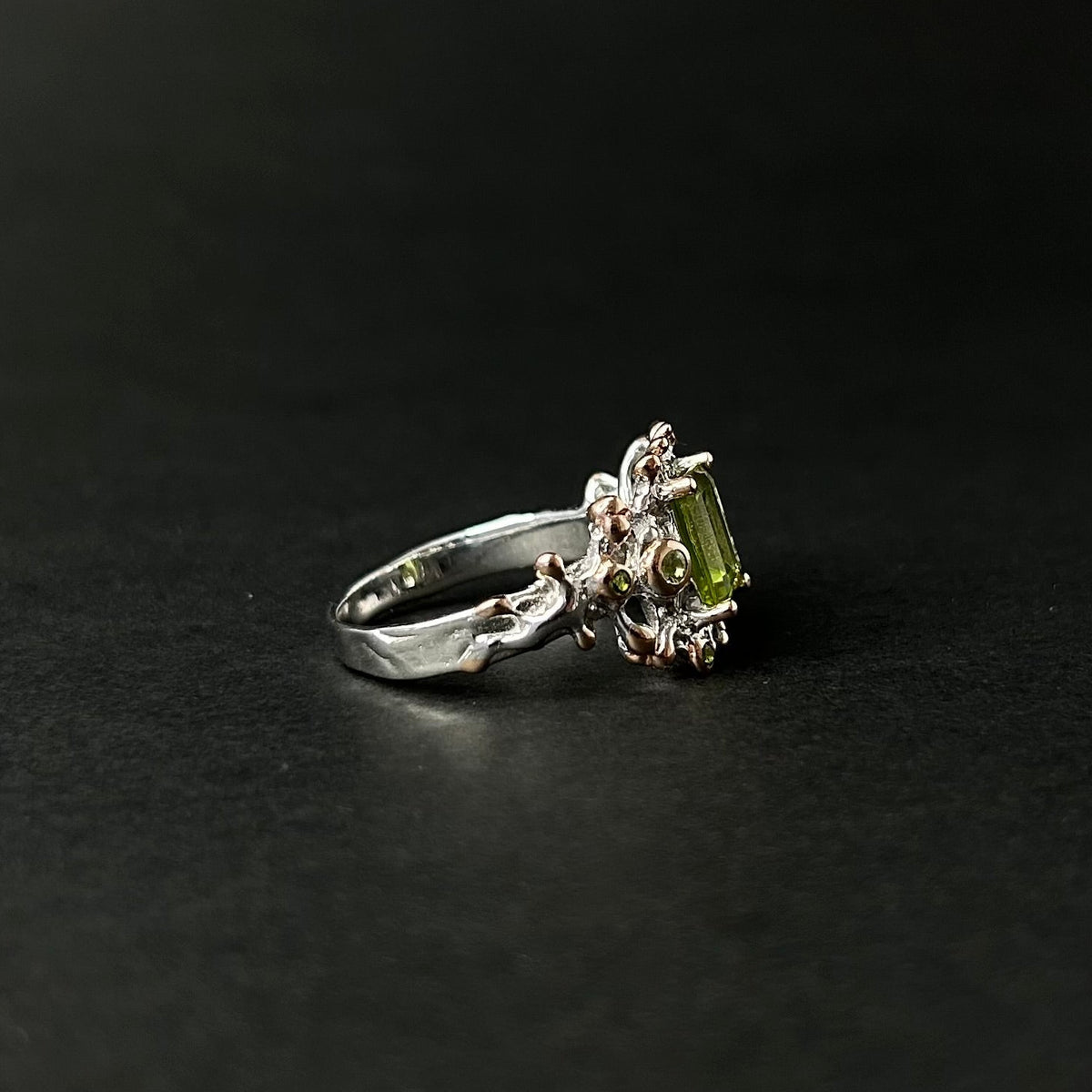 Silver ring with a green gemstone on a black background