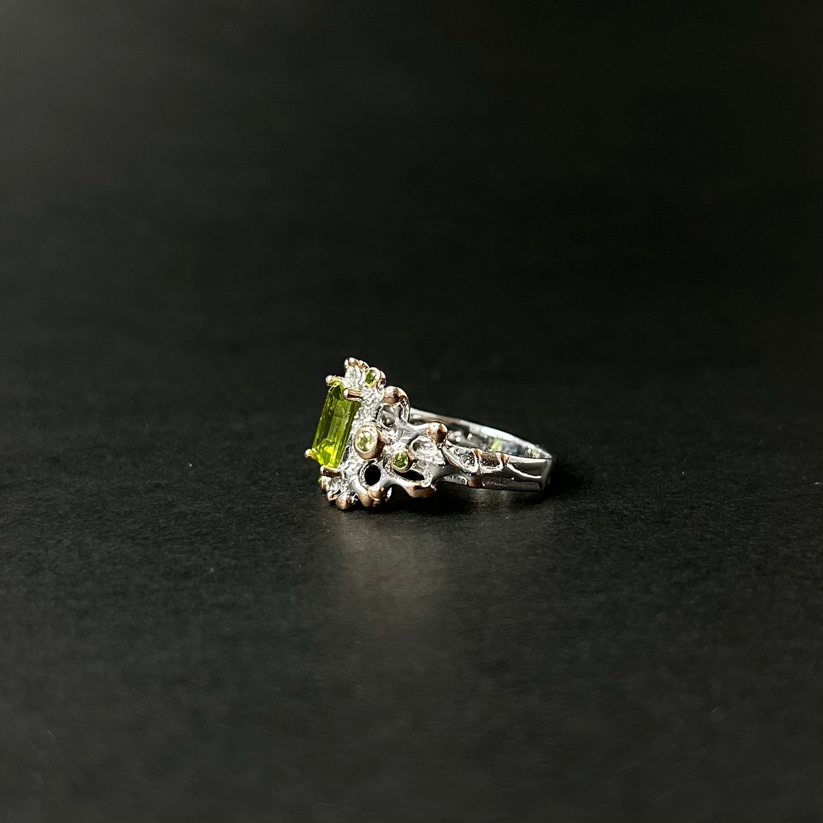 Silver ring with green peridot gemstone on a black background