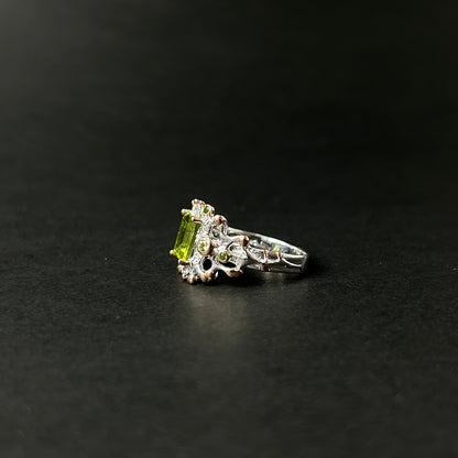 Silver ring with green peridot gemstone on a black background