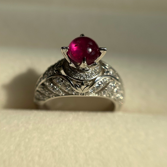 Silver ring with a red ruby on a beige background