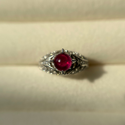 Silver ring with a red ruby on a beige background