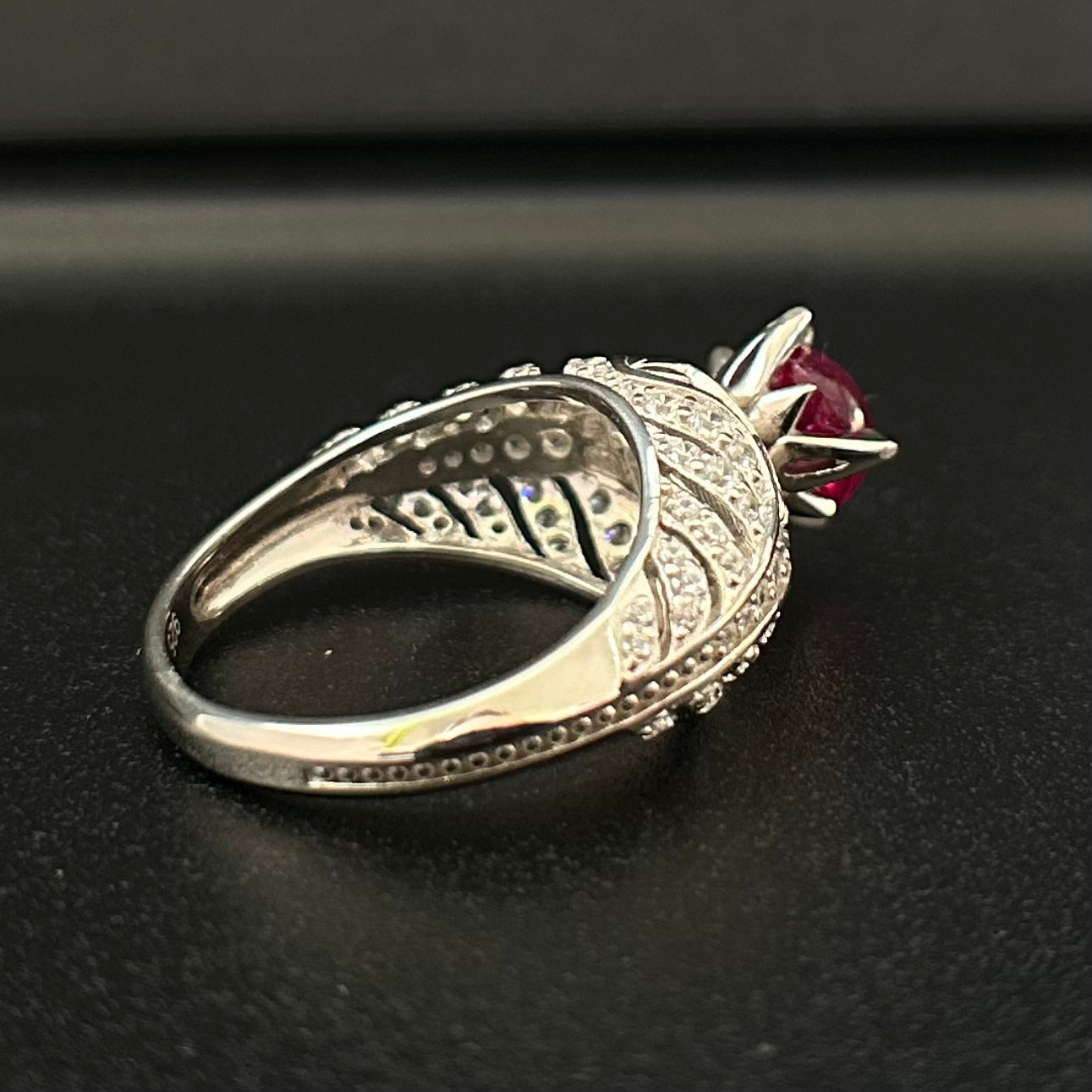 Silver ring with a red ruby on a black surface