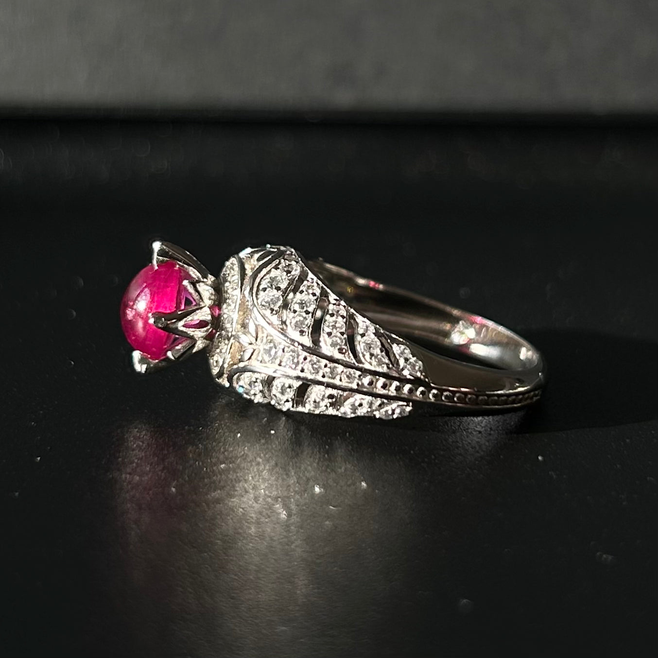 Silver ring with a red ruby on a black surface