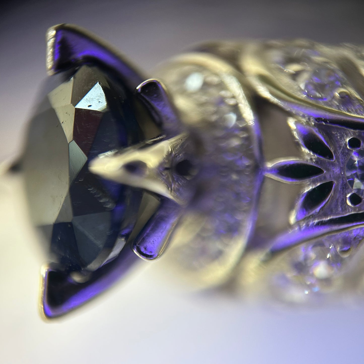 Close-up of a decorative silver ring with intricate designs and a purple sapphire.