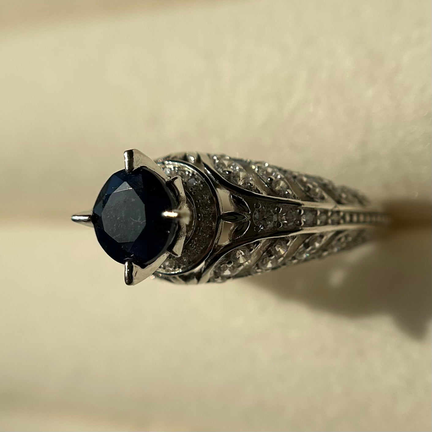 Silver ring with a blue sapphire on a beige background