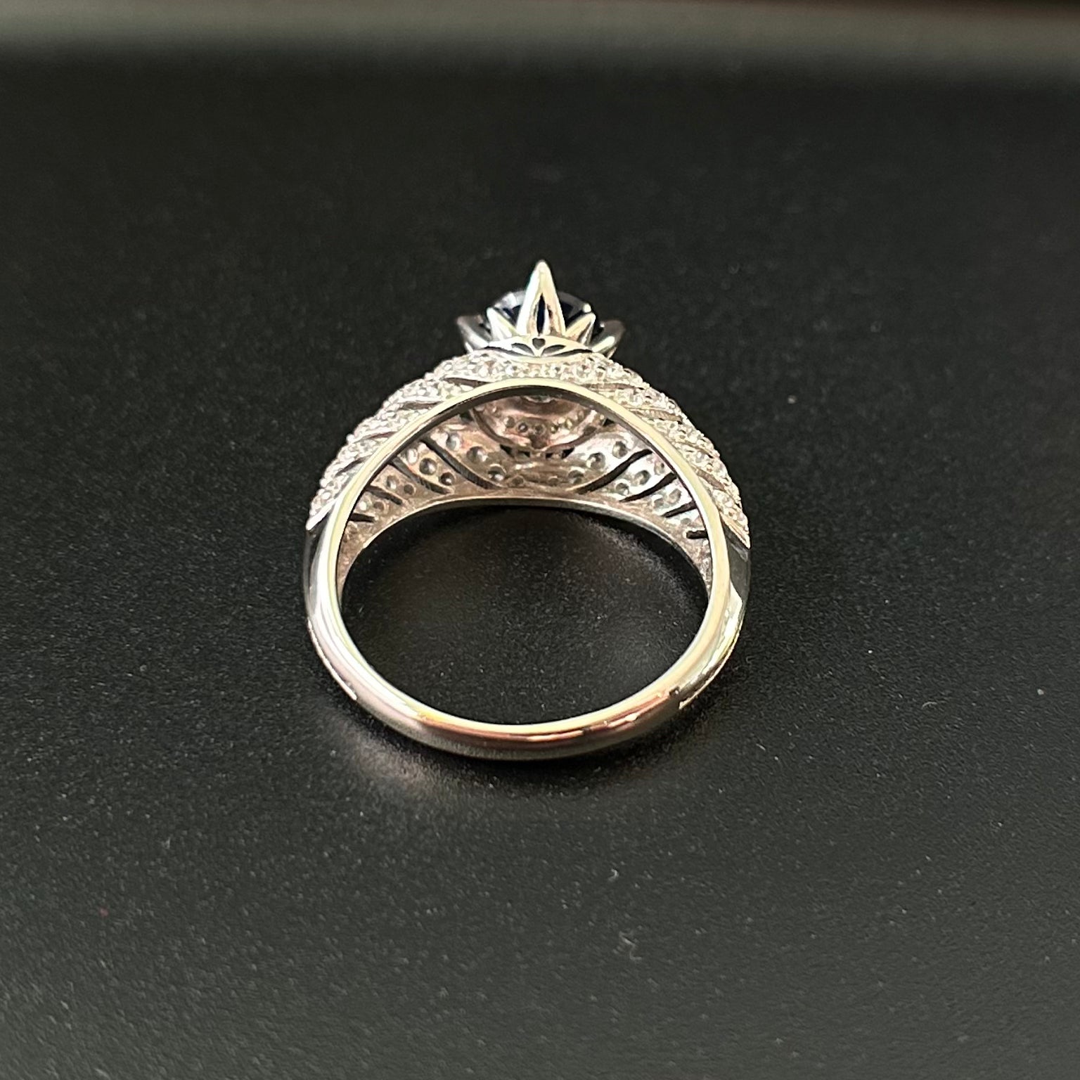 Silver ring with intricate design on a black background