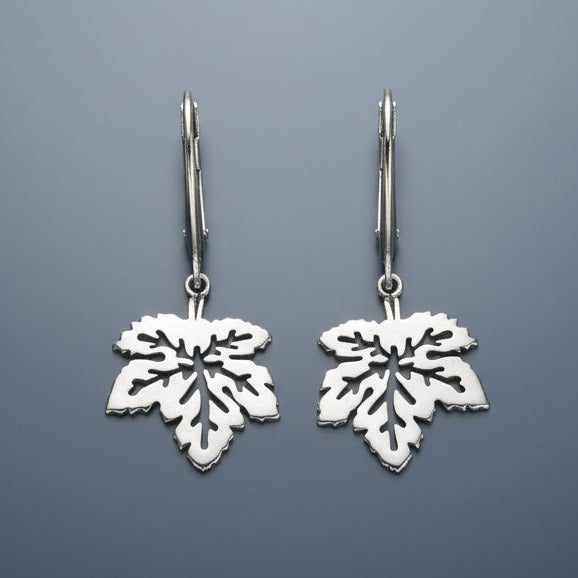Silver leaf-shaped earrings on a gray background