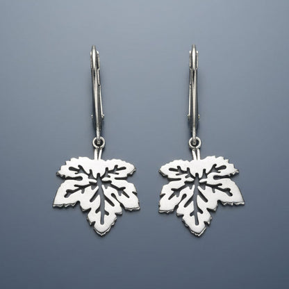 Silver leaf-shaped earrings on a gray background