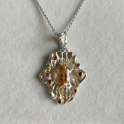 Gold and silver pendant with a central gemstone on a light gray background