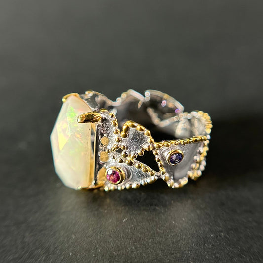Silver ring with opal stone and gemstones on a dark background