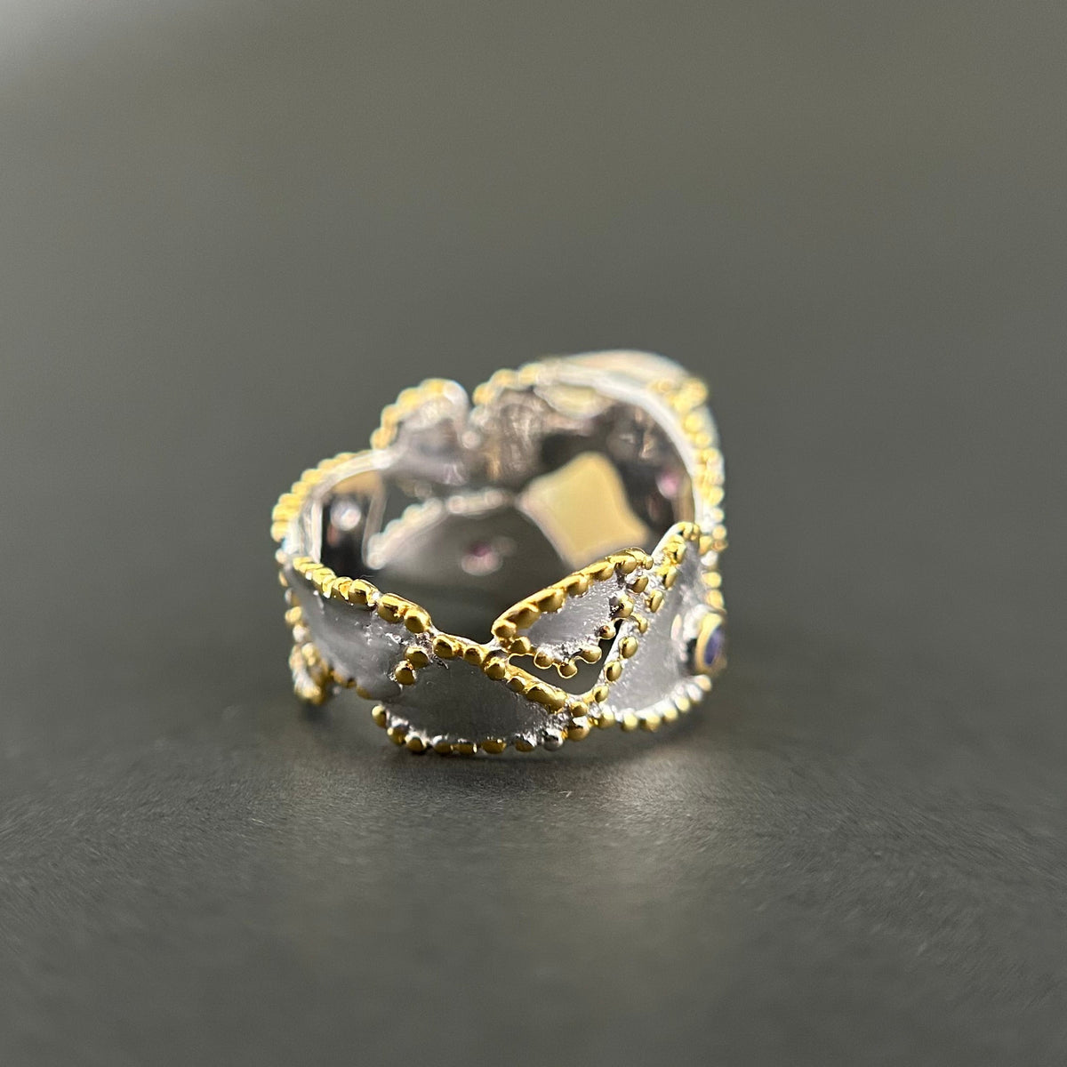 Silver ring with gold accents on a dark gray background
