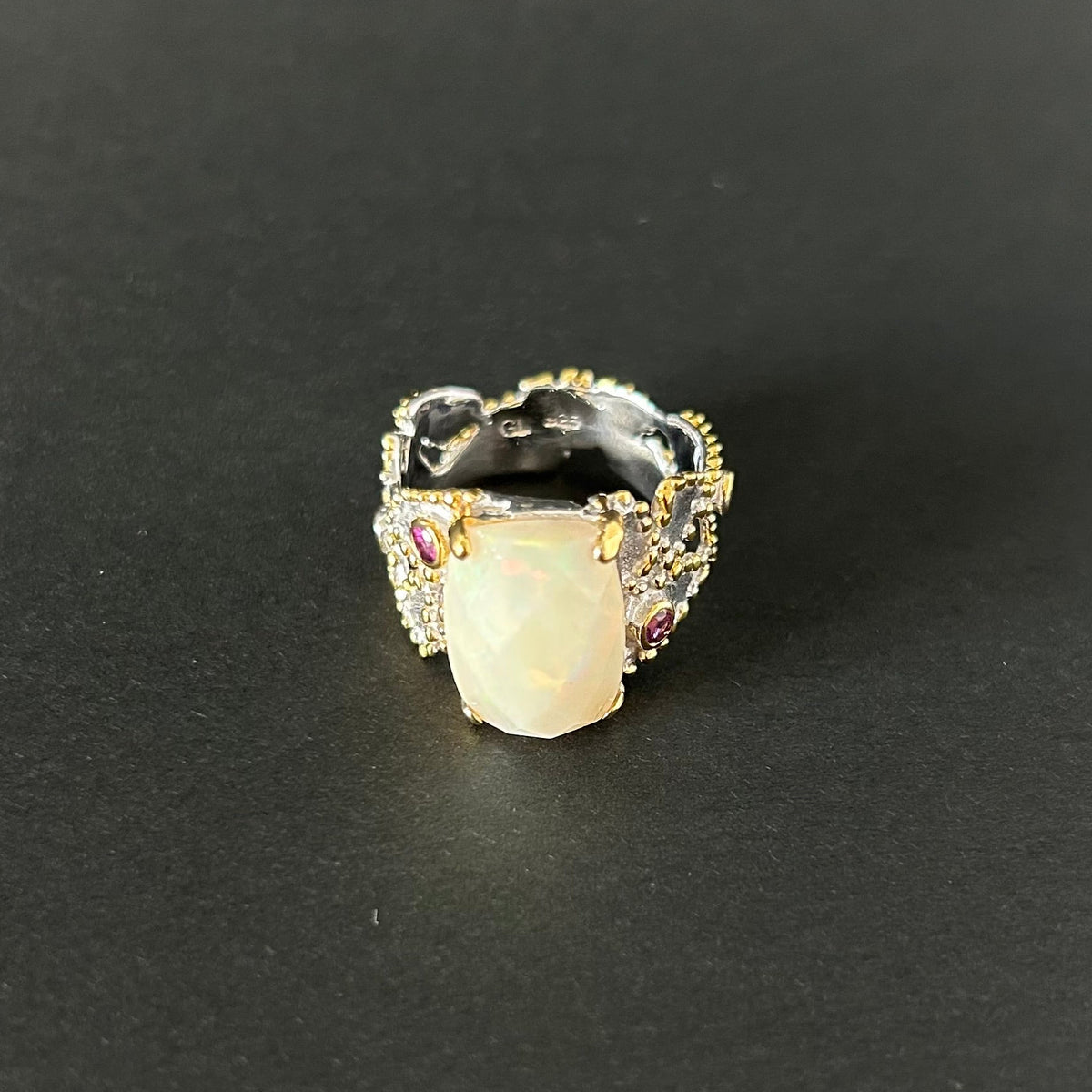Ring with a large central opal and smaller stones on a black background