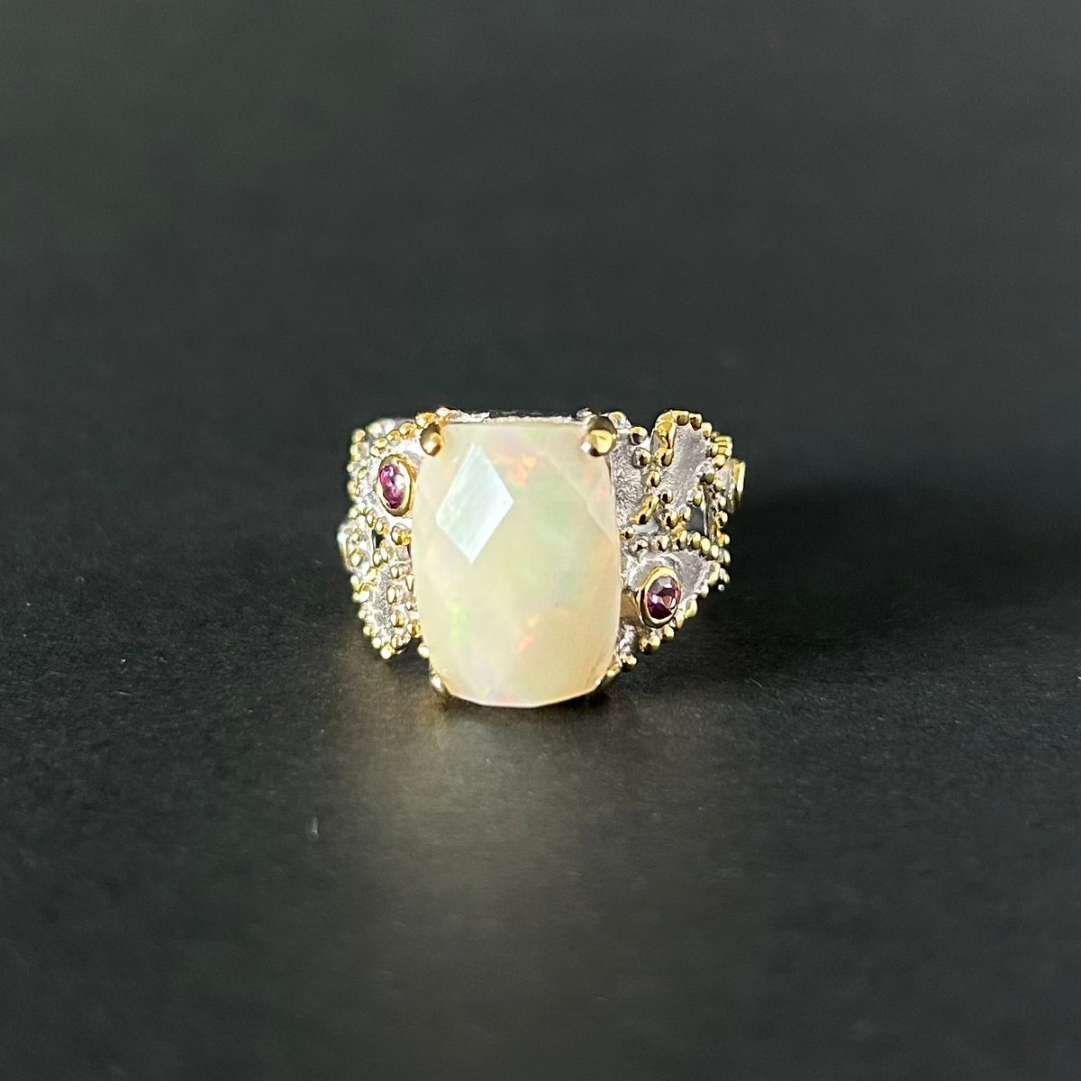 Silver ring with a large central opal and smaller stones on a black background