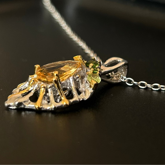 Gold and silver pendant with green gemstone on a dark surface