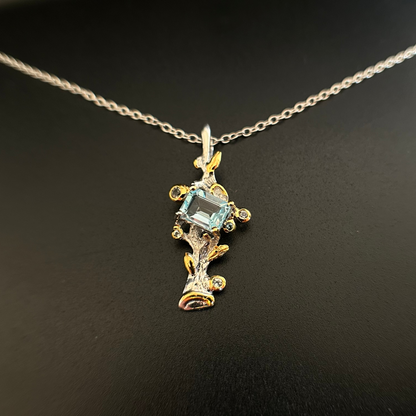 Silver pendant with 22k gold plating and a central Topaz on a black background